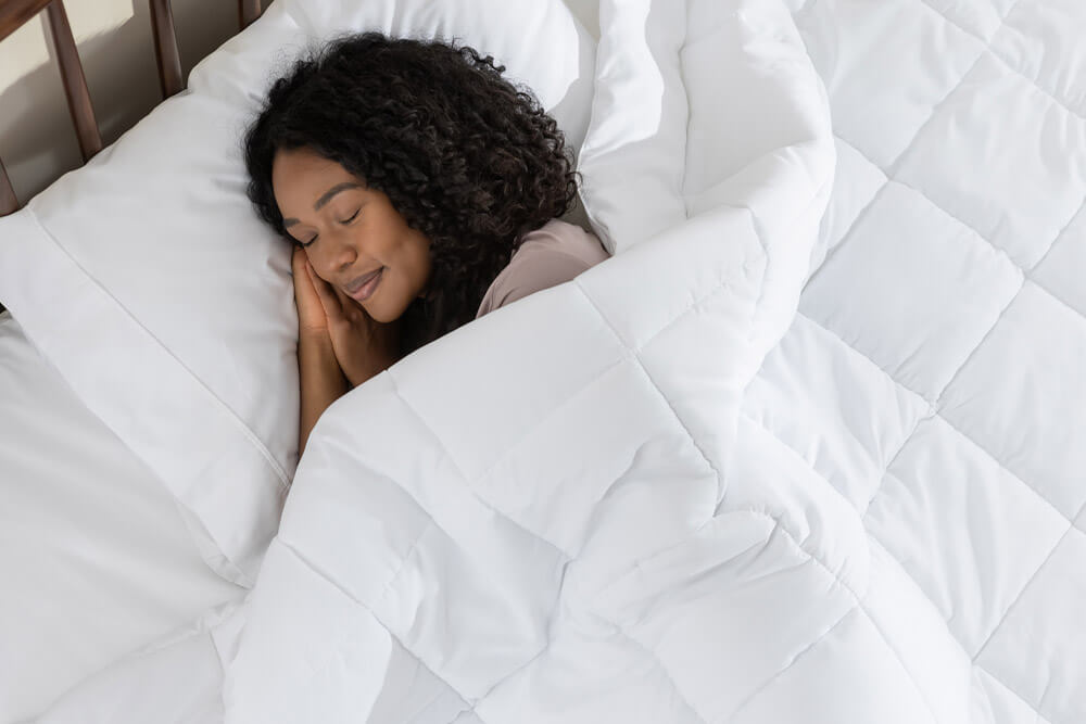 Une femme dort paisiblement sous sa couette en duvet synthétique.