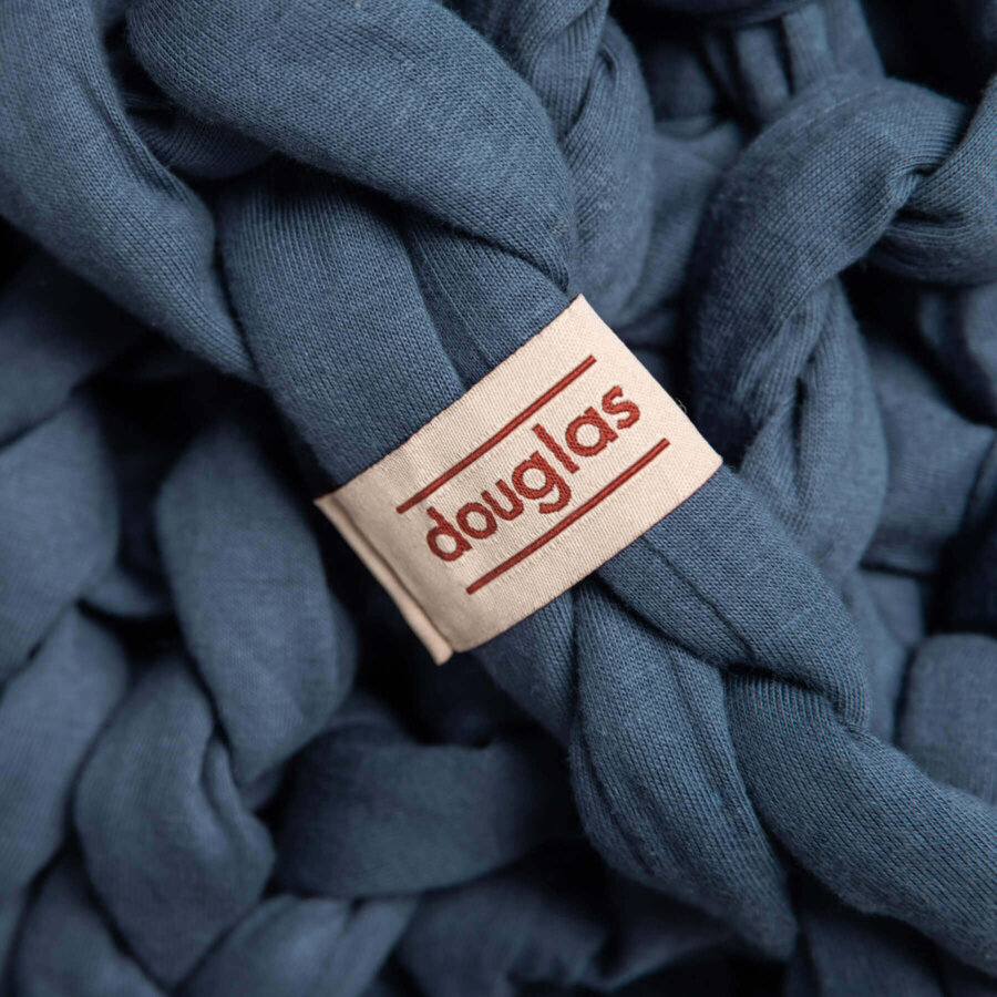 Close up showing the braids and Douglas logo on a navy blue Douglas Hand Knit Weighted Blanket