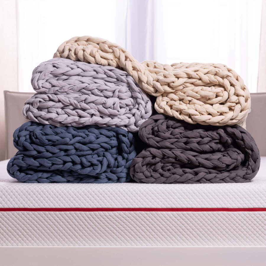 Stack of four neatly folded Douglas Hand Knit Weighted Blankets showing each of the four available colours
