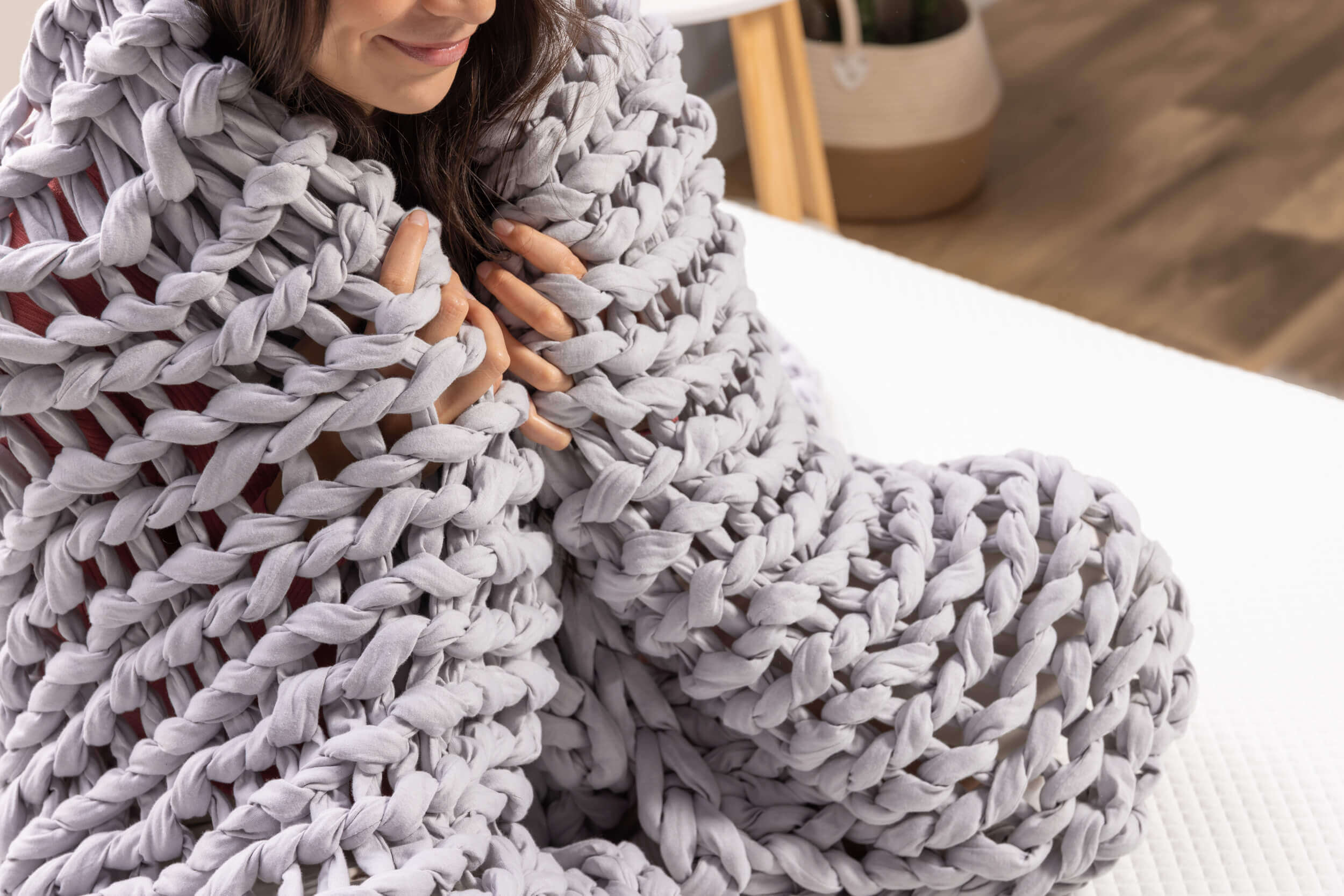 Woman snuggles the Douglas Hand Knit Weighted Blanket around her shoulders