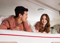 A man and a woman lying on a Douglas RV mattress on the top bunk of a motorhome