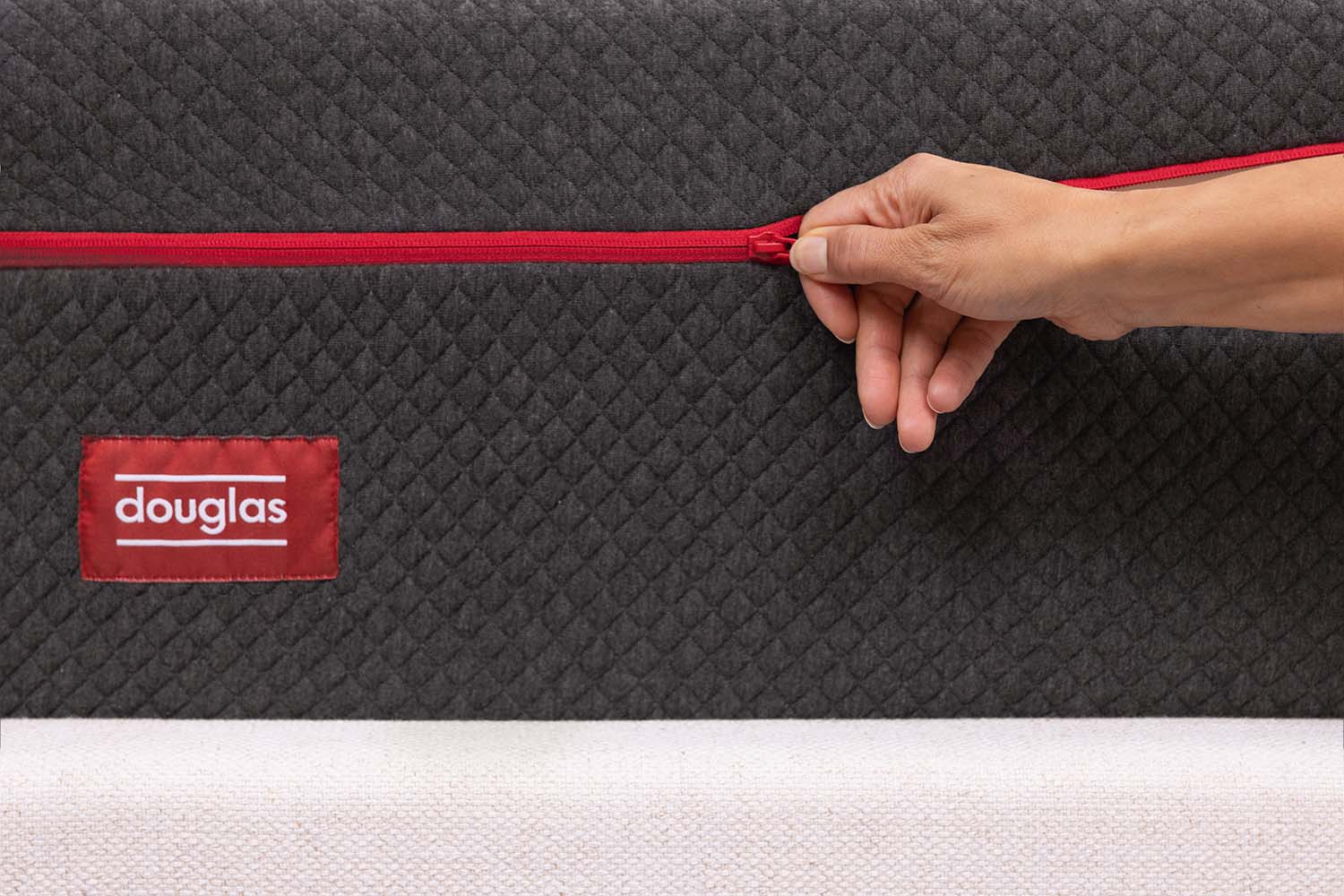 Woman unzipping the machine-washable cover on a Douglas Alpine Hybrid mattress