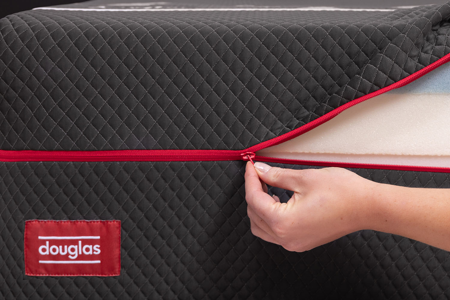 Woman unzipping the machine-washable cover on a Douglas Summit Hybrid mattress