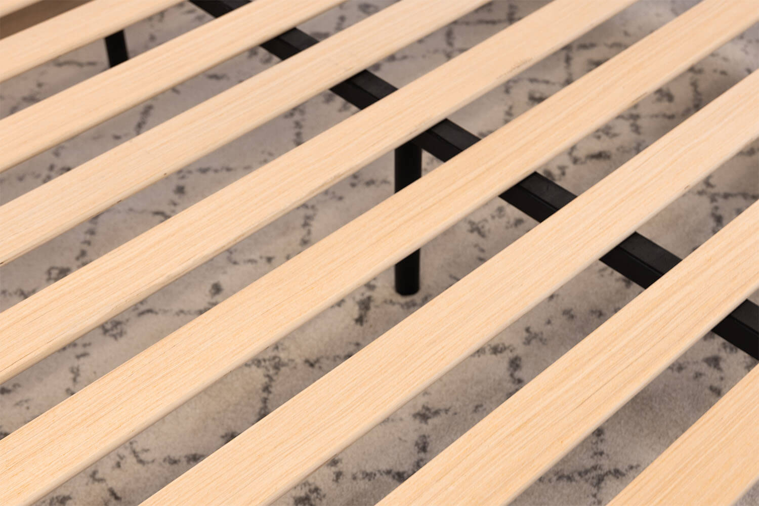 Vue détaillée des lattes de bois et de la poutre centrale en acier de la base de lit plateforme.