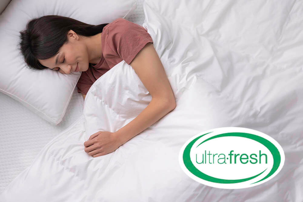 Woman sleeping in bed under Douglas Down Duvet with superimposed Ultra-Fresh® logo