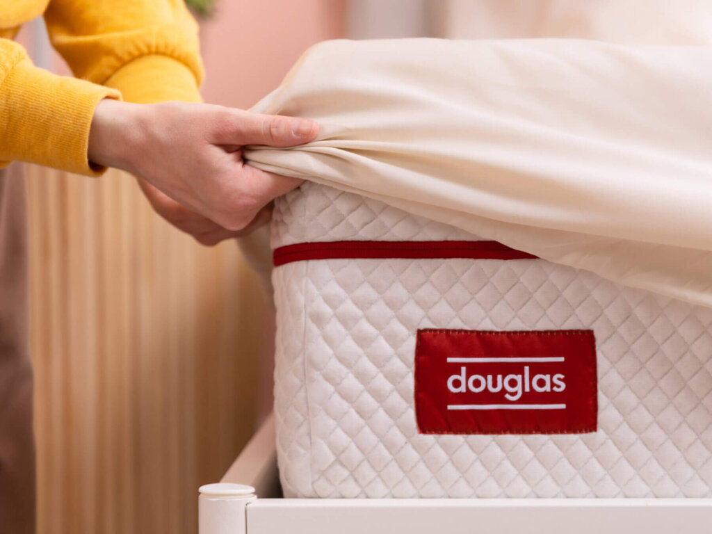 Woman pulling the Douglas Egyptian Cotton Sheets fitted sheet over the corner of a Douglas mattress