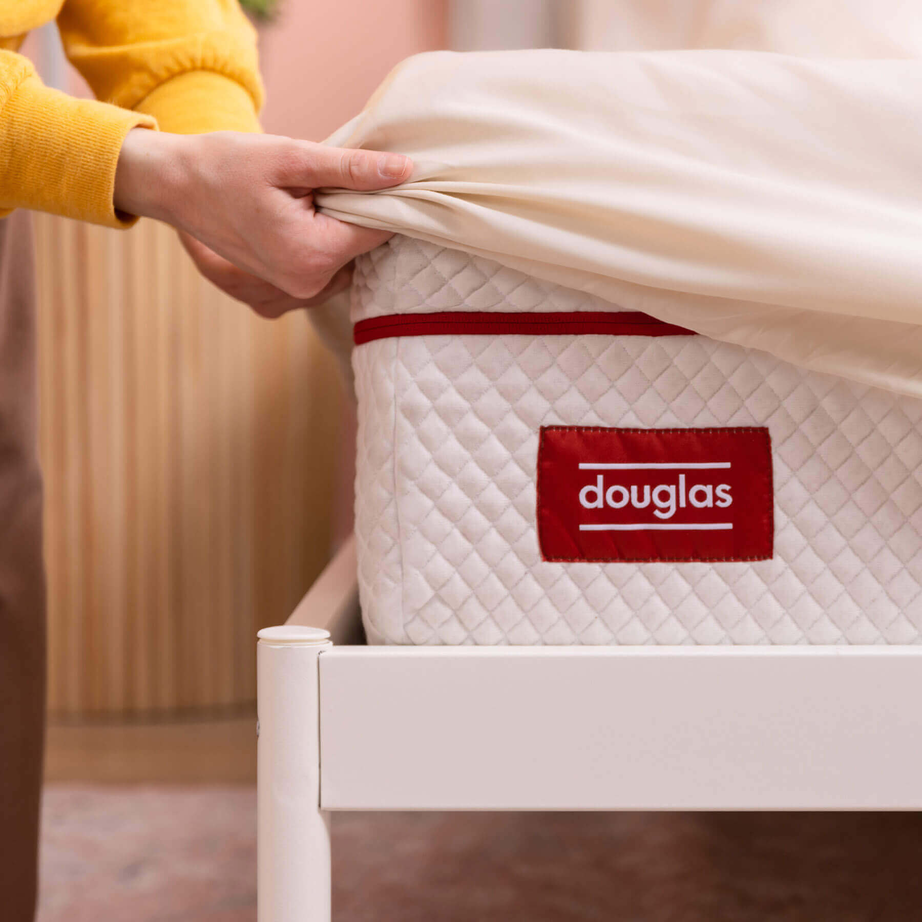 Egyptian-Cotton-Sheets-Carousel-7 Woman pulling the Douglas Egyptian Cotton Sheets fitted sheet over the corner of a Douglas mattress