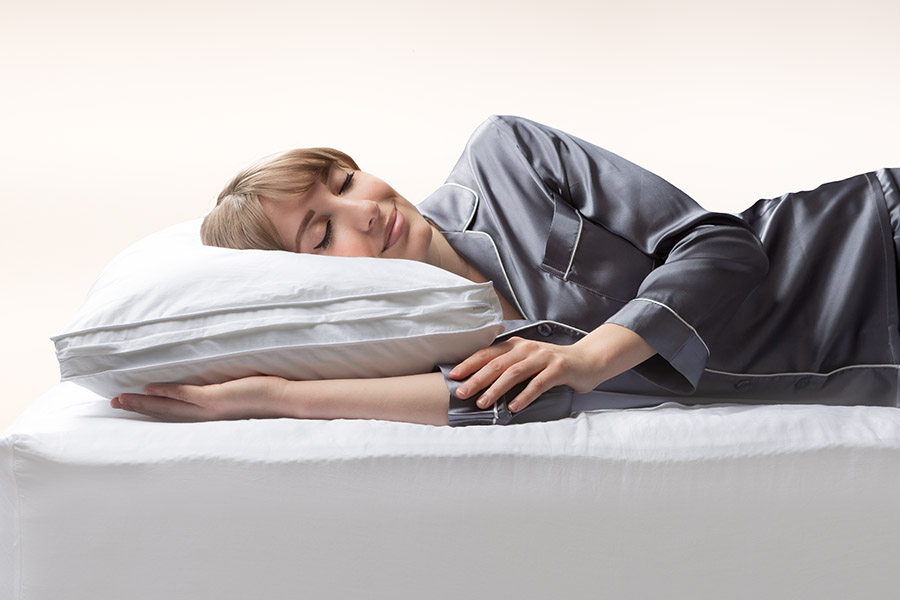 Une femme dort paisiblement sur le ventre avec la tête sur l’oreiller en microfibre Douglas.