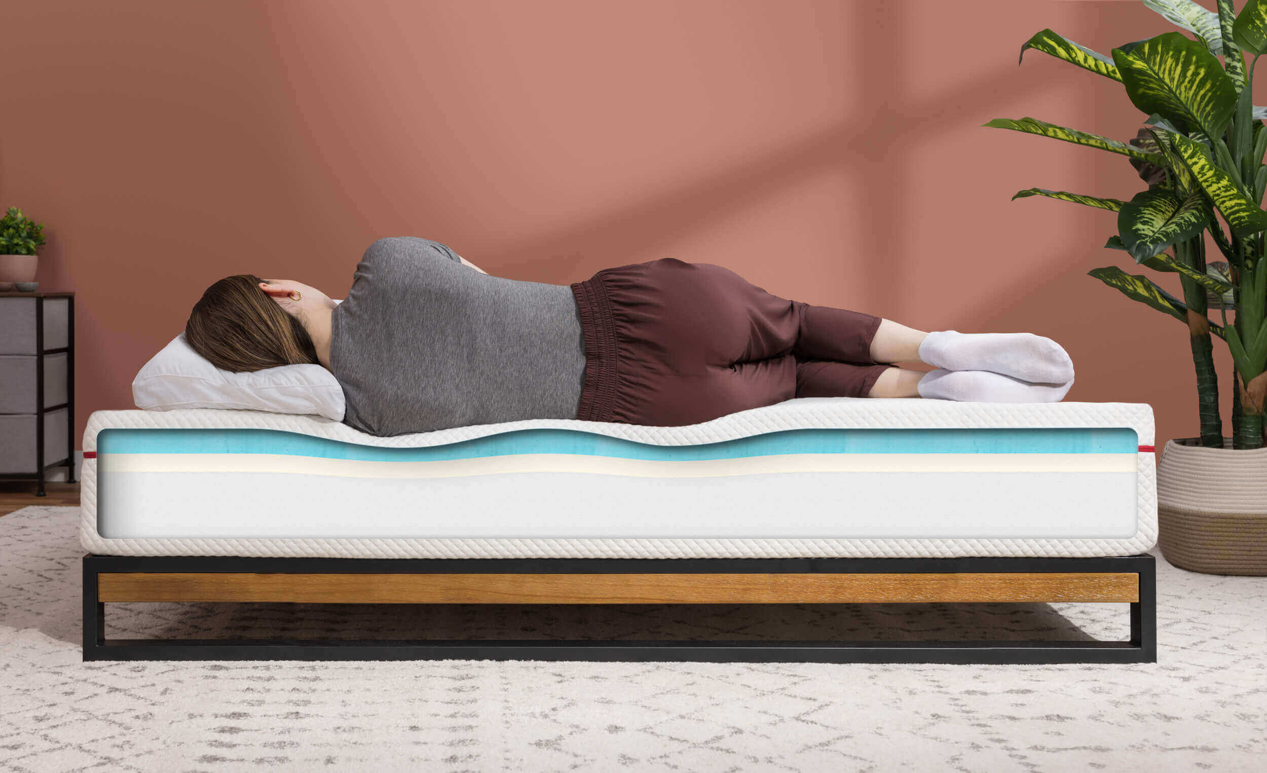 A woman sleeps on a Douglas mattress, which shows a cross section of its layers to display body contouring and how the Douglas mattress provides spinal alignment.