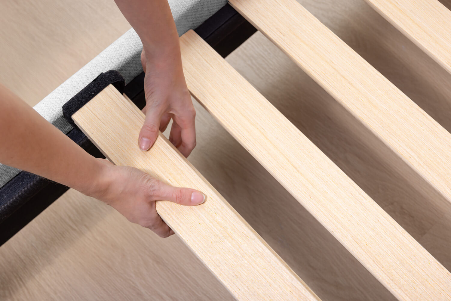 Close up of a person installing the wood slats with Velcro on the Platform Bed.