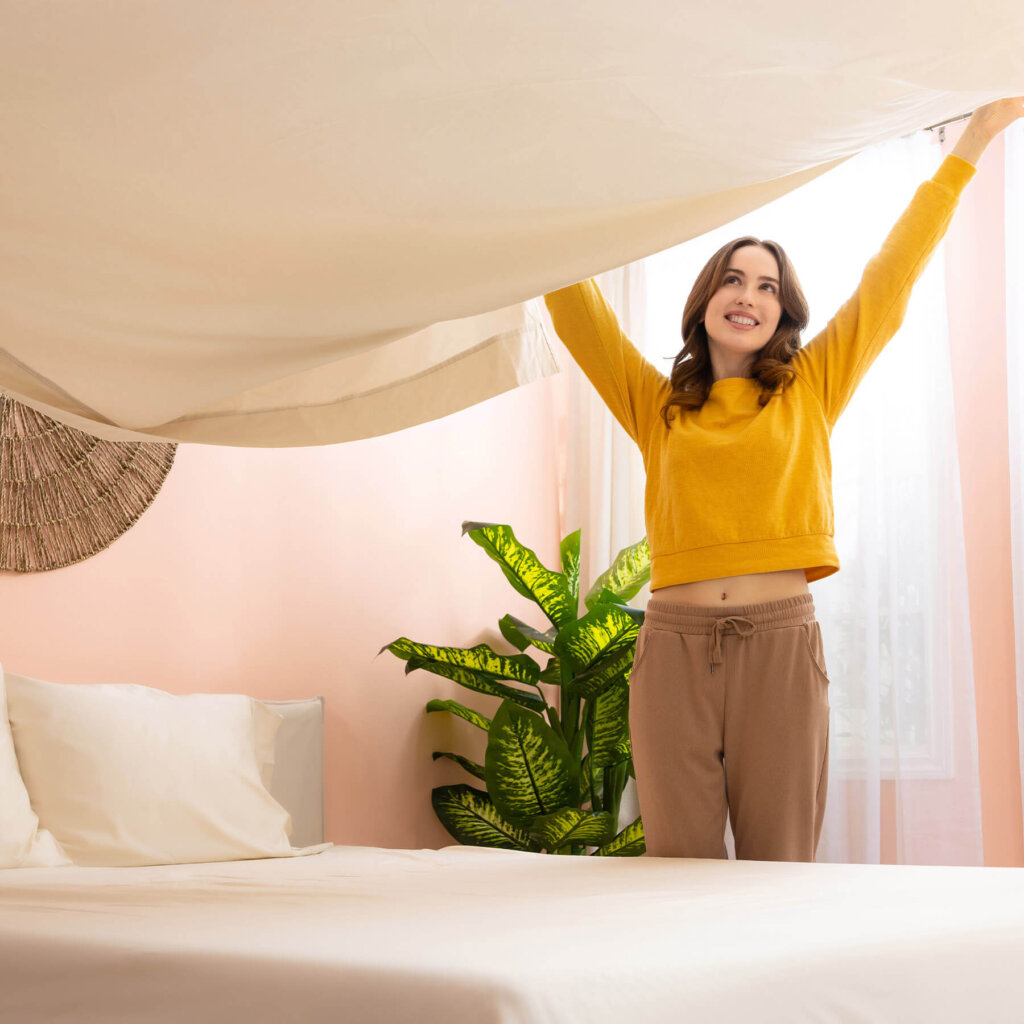 Woman spreading the top sheet of her Douglas Egyptian Cotton Sheets on to her bed