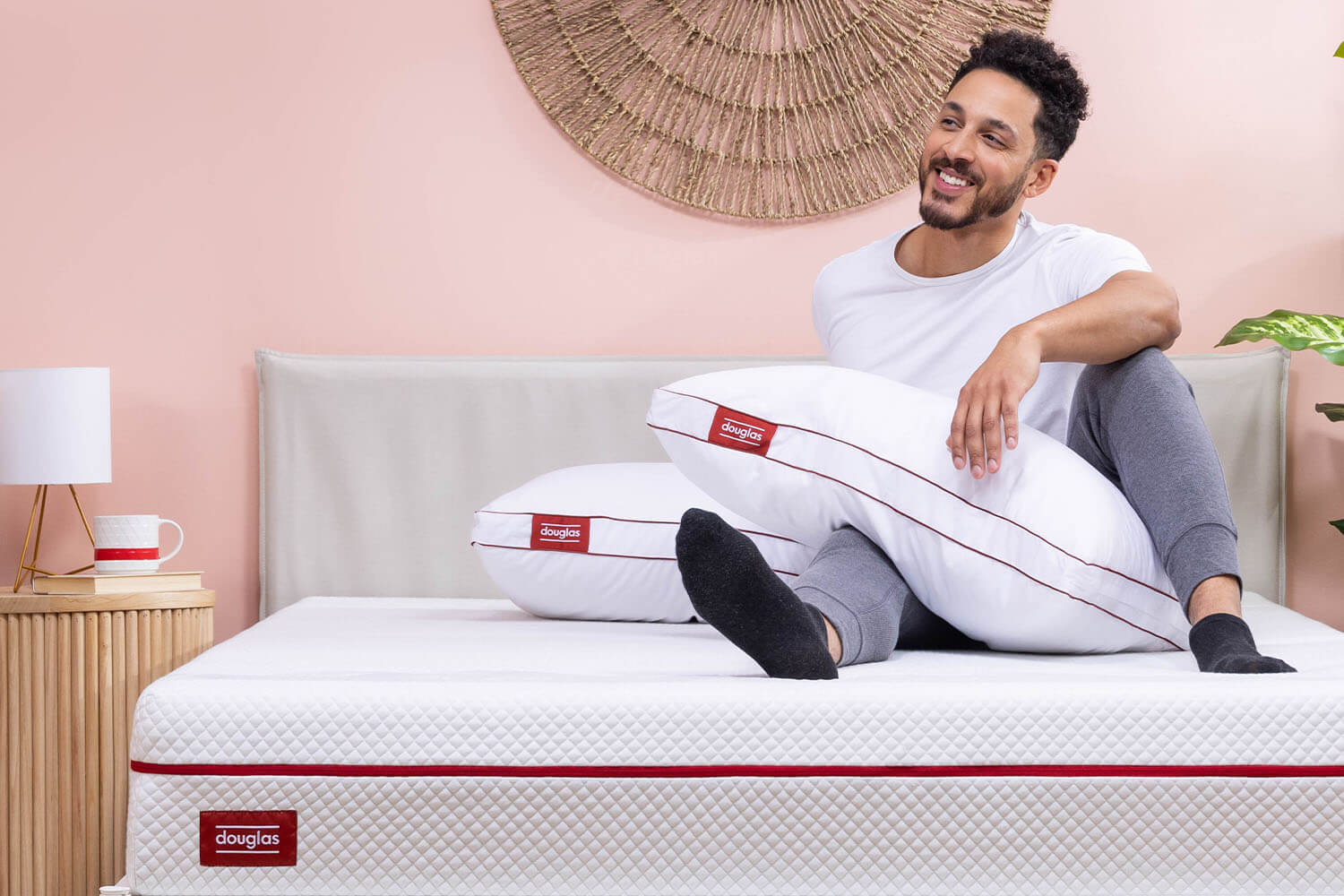 A man holds his two free pillows that he recieved with his Douglas mattress purchase.