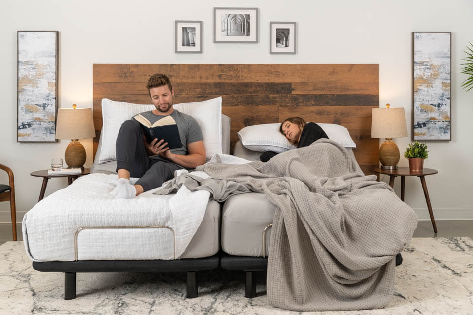 A man reads while a woman rests in their Podium adjustable bed