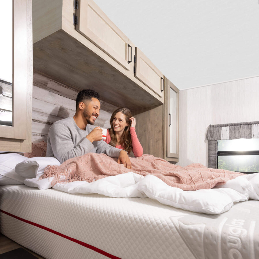 Man and woman sitting on a Douglas Summit RV mattress in their RV bedroom